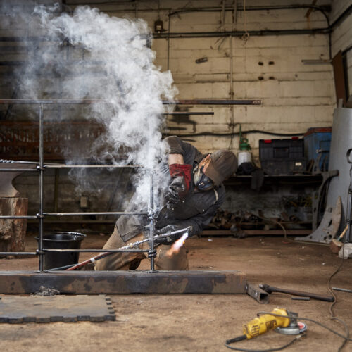 Artist Metalworker,england,artisan Metalworker At Work In A Workshop Working, Soldering A Metal Fence.